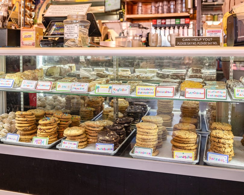 A bakery display case filled with various cookies, brownies, and banana bread loaves.