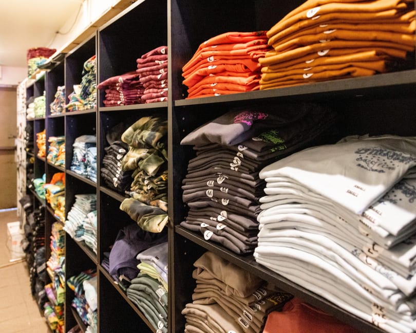 Shelves filled with neatly folded t-shirts and sweatshirts in various colors and patterns.