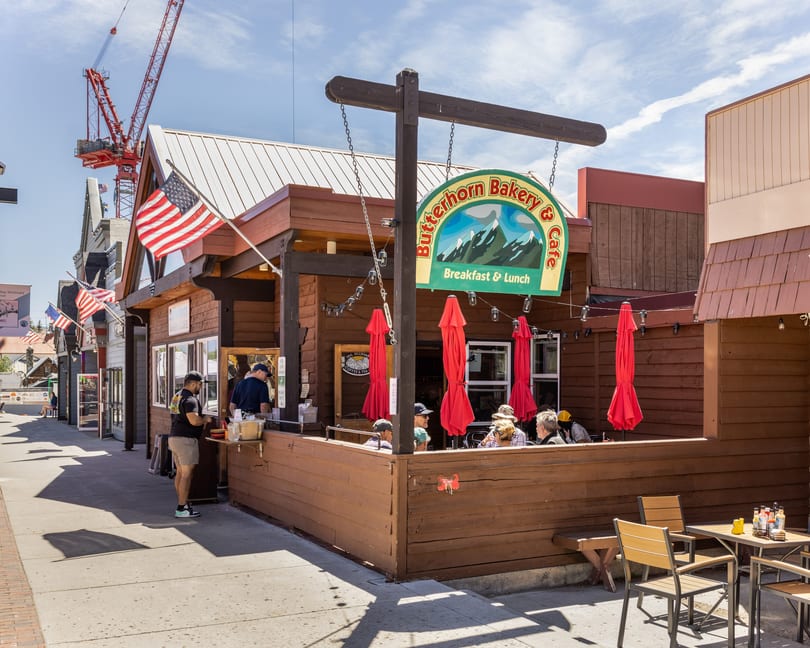 Butterhorn Bakery & Cafe with outdoor seating, red umbrellas, and people dining on a sunny day.