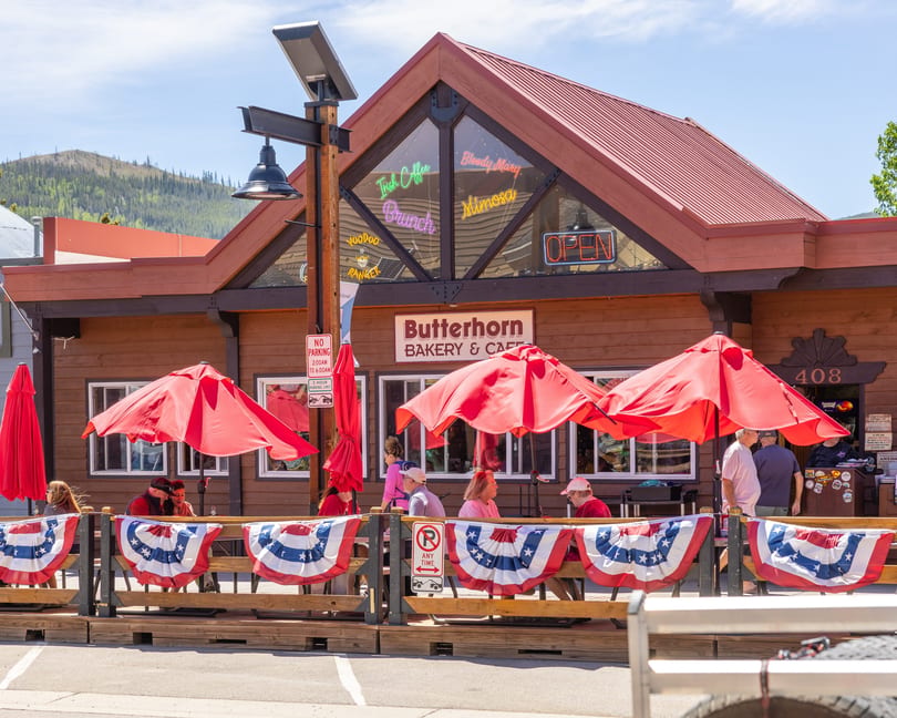 Butterhorn Bakery & Cafe with outdoor patio seating, red umbrellas, and American flag bunting.