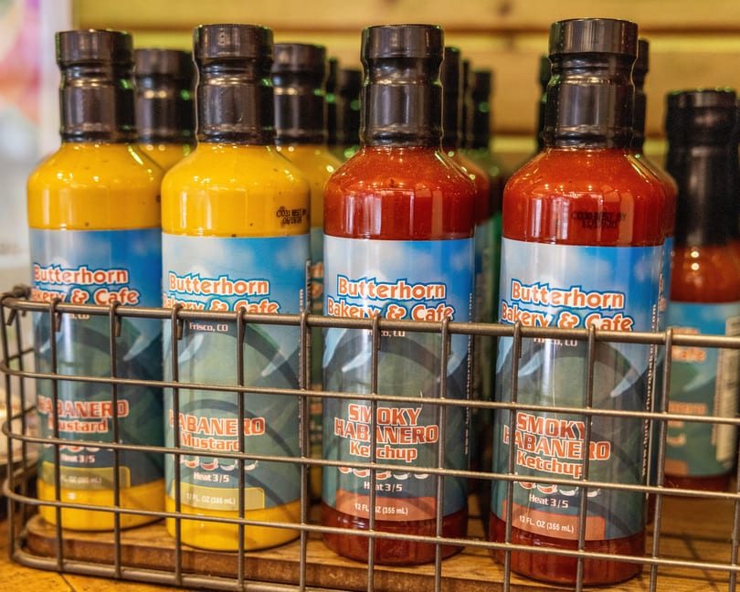 Bottles of Butterhorn Bakery & Cafe's habanero mustard and smoky habanero ketchup in a wire basket.
